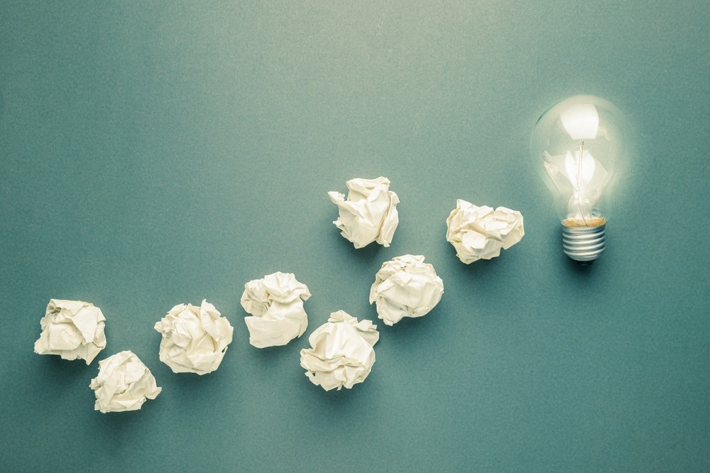Glowing light bulb at the final of the crush paper balls trace, lesson learned, mistake, leads to success idea
