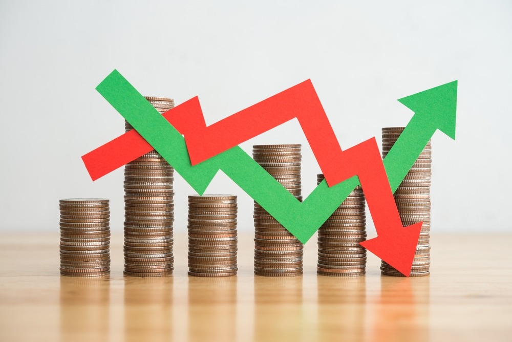Stack coins and arrow red green graph chart volatility up and down on wooden table background.
