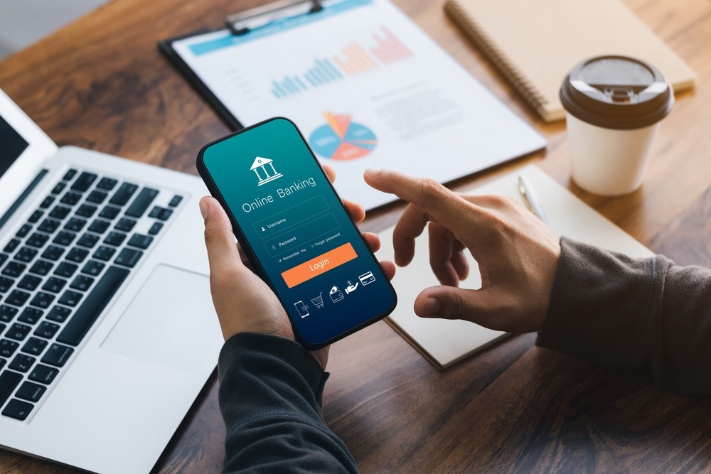 Male executive using smartphone to conduct online mobile banking, investing in stocks and mutual funds, retirement investment ideas.