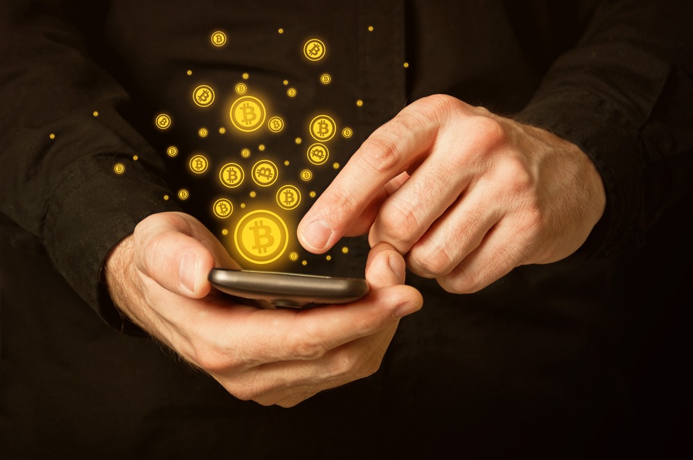 Hand with mobile smart phone and bitcoin currency symbol