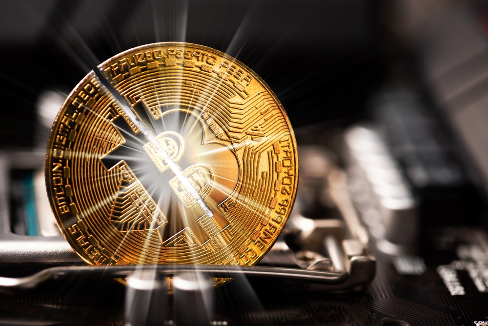 shutterstock_1733730203-1 Cryptocurrency bitcoin with cutting traces in the middle on computer mainboard.